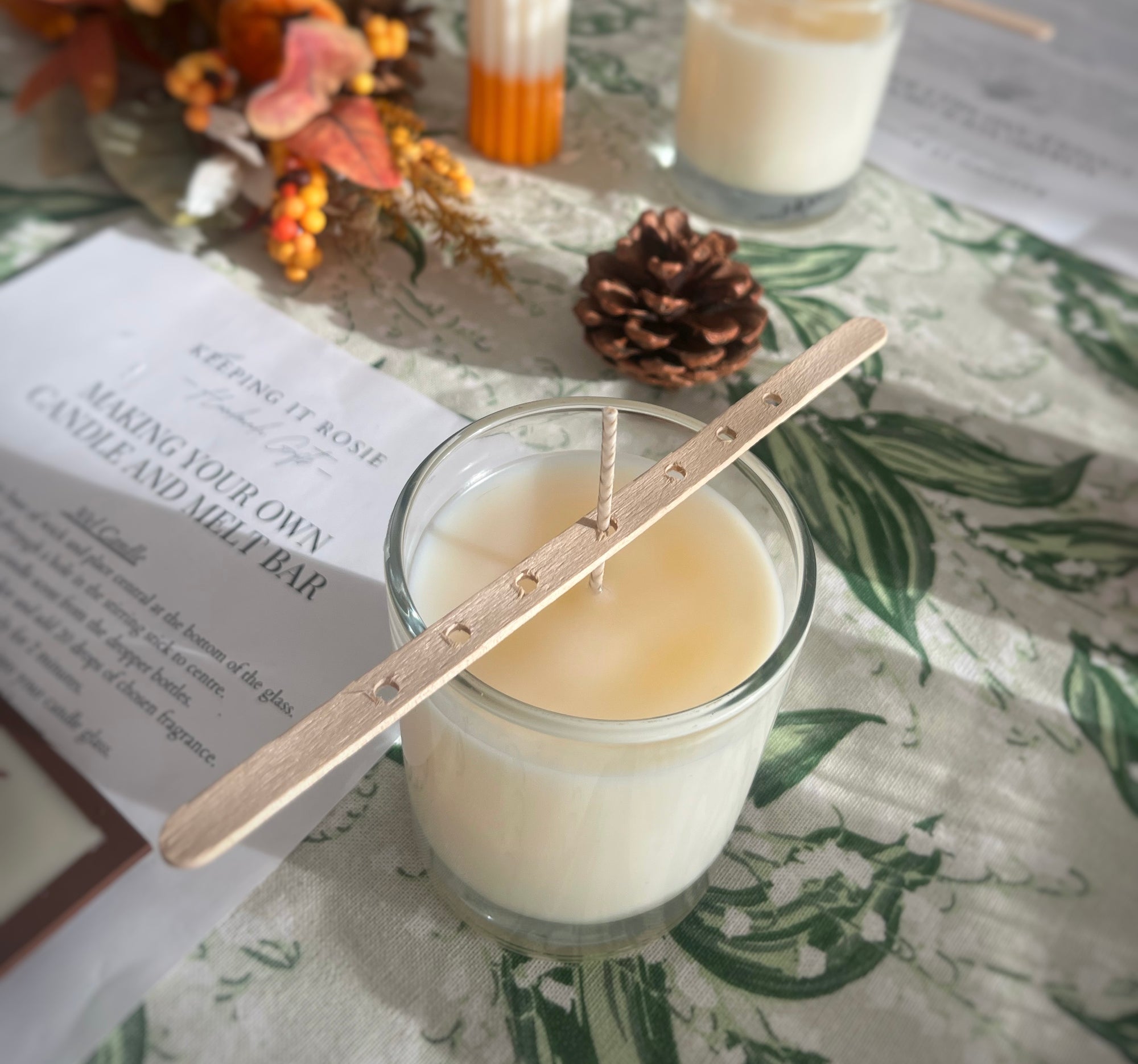 Candle with wooden wick holder on a table with decorative elements, during a candle making workshop